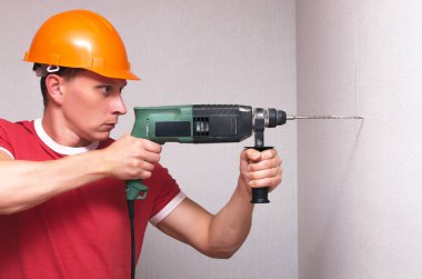 Oluşturucu çalışan bir duvar ile bir perforator girer. Ev onarım kavramı.