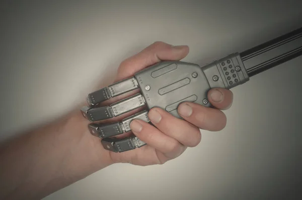 Handshake between hand of human and robot hand isolated on gray background. Future concept.