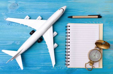 Oyuncak uçak, mavi ahşap masa arka plan üzerinde boş sayfa Not defteri ve gezinti pusula.
