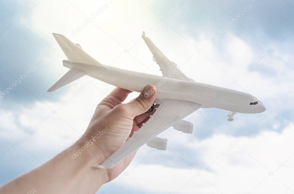 Toy airplane in the man hands on blue sky background. Air transportation concept.