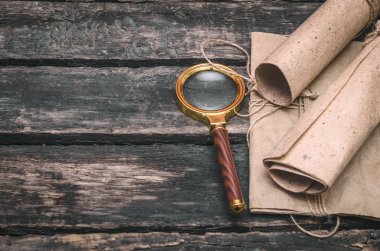 Kağıt belge kaydırma ve Büyüteç Camı ahşap Resepsiyon arka plan üzerinde.
