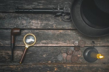 Misket tüfeği silah, Sigara boru, Büyüteç Camı, para, melon şapka ve ahşap masa arka plan üzerinde yanan muma. Dedektif aracı tablo.
