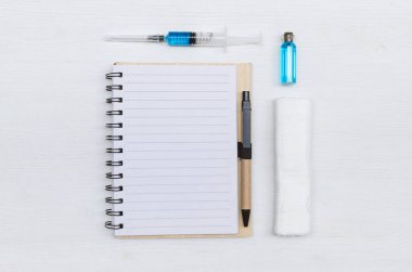 Şırınga, boş sayfa Not defteri, bandaj ve ampul ile mavi sıvı ilaç Doktor masada. Tıbbi dergi veya doktor reçete mockup.