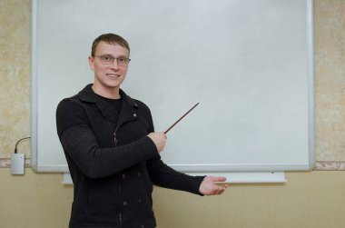 Öğretmen adam blackboard tarafından duruyor ve tarafından bir okul işaretçi üzerinde gösterilen sınıfta bir ders Tema kopya alanı.