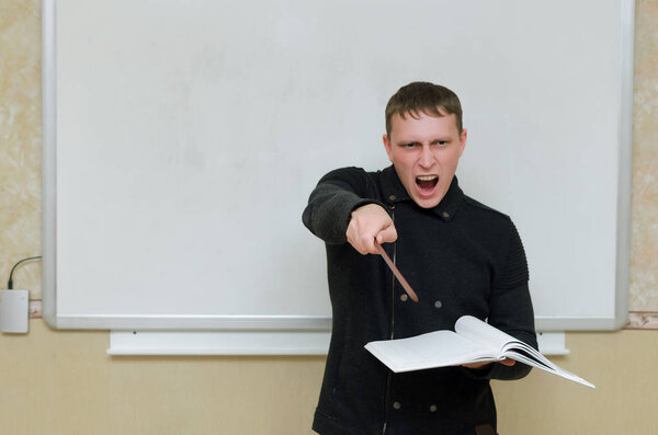 Angry teacher with class book is standing by the blackboard and shouting on the student for they do not ready to lesson.