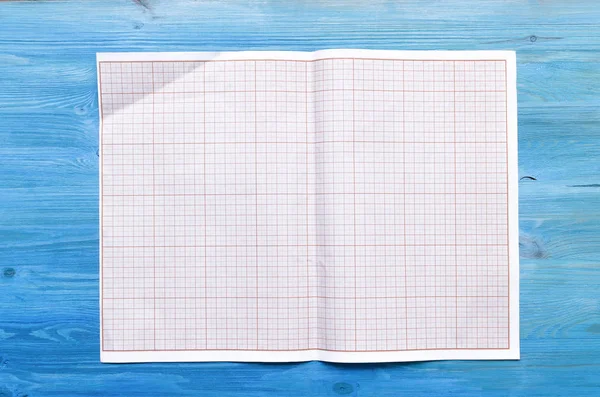 Graph paper for project drafts with copy space on blue wooden table background.