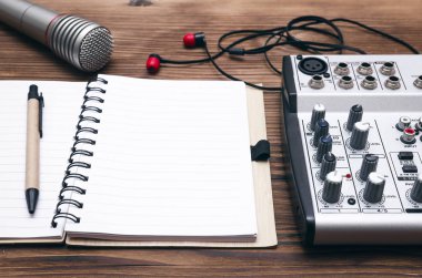 Ses kayıt stüdyosu kavramı. Karaoke. Şarkı sözleri. Mikrofon, ses ses mikseri, boş sayfa Not defteri ve masanın üzerinde kulaklık.