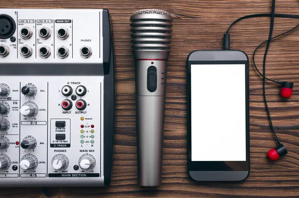 Mobile phone with blank screen, microphone, audio sound mixer and headphones on the table. Audio recording studio concept. Karaoke. Song lyrics.
