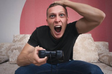 Bir elinde gamepad ile kızgın oyun adam video oyun oynuyor ve başını başka bir el tarafından tutuyor. Bir oyun kavramı kaybetmek.
