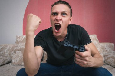 Gamepad el ile agresif oyun adam video oyun oynuyor ve yumruk sallıyor. Bir oyun kavramı kazanmak.