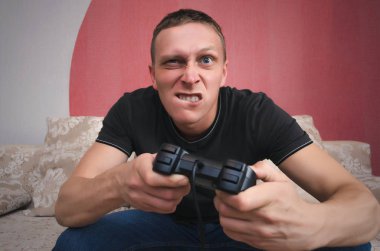 Kızgın, gergin oyun adam elinde gamepad ile video oyun oynuyor. Gergin bir oyun.