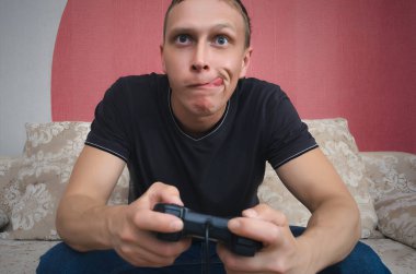 Onun elinde bir joystick ile coşkulu oyun adam kanepede oturuyor ve video oyun oynuyor. Heyecan verici ve ilginç oyun kavramını