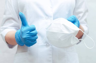 Doktor elinde tıbbi maske mavi Medikal eldiven giymiş. Bir tıbbi maske kullanmak bir hastalık önlemek için.