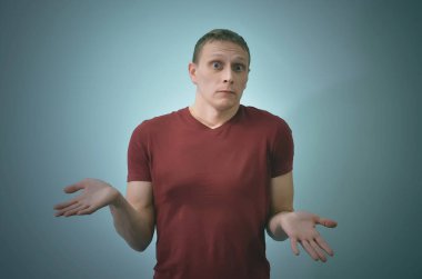 Suçlu adam duruyor ve omuzlarının üzerinde mavi arka plan izole shrugging.