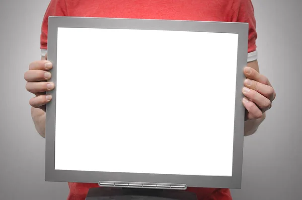 男子拿着一个电脑显示器与空白屏幕在他面前隔离在灰色背景 — 图库照片