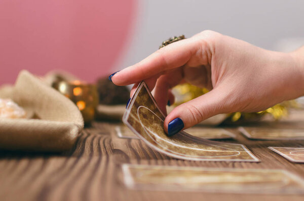 Tarot cards and hands of fortune teller on wooden table background.