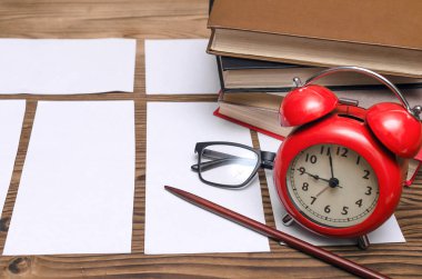 Boş sınav biletleri, kitaplar, okul işaretçi, gözlük ve sınıfta okul masasında kırmızı bir çalar saat. Eğitim arka plan. İş test etmek için zaman.