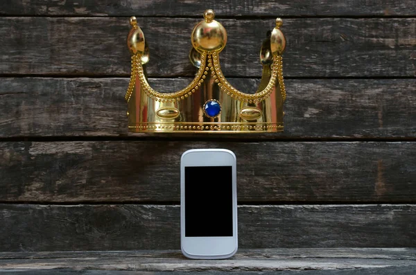 Mobile phone with blank screen and golden crown above it. Premium vip support hotline consulting concept.