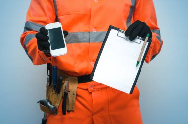 Bina sözleşme. Düzeltme listesi. Oluşturucu Not defteri ve boş ekran ile cep telefonu elinde tutuyor. Bir tamirci ara. Bina anlaşması mockup. Ölçü sonuçları veya inşaat bill kavramı.