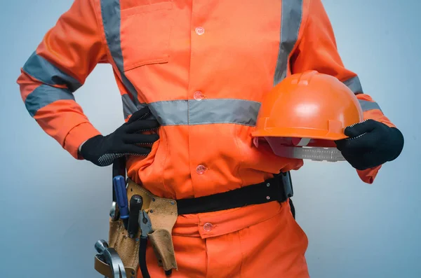 ビルダー建設労働者の つを保持しているハード帽子を手 ツールで彼のベルトに別の手を保持しています 建設コンセプトの下 — ストック写真