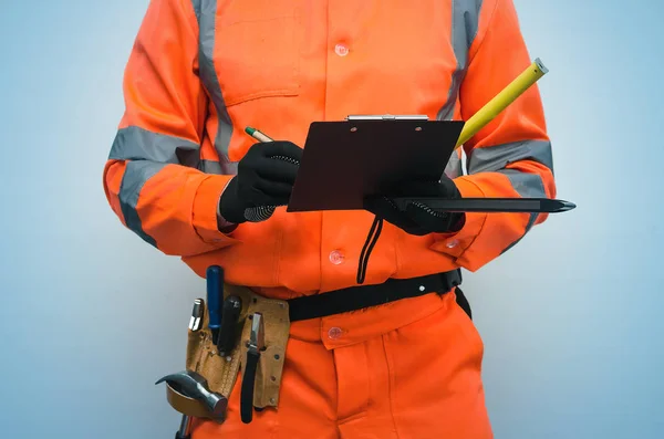 The measurer worker writes dimensions to his notebook. Building contract signing. Builder with construction project plans in the hands isolated on blue background.