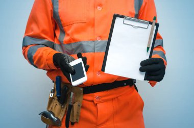 Bina sözleşme. Düzeltme listesi. Oluşturucu Not defteri ve boş ekran ile cep telefonu elinde tutuyor. Bir tamirci ara. Bina anlaşması mockup. Ölçü sonuçları ya da inşaat bill.