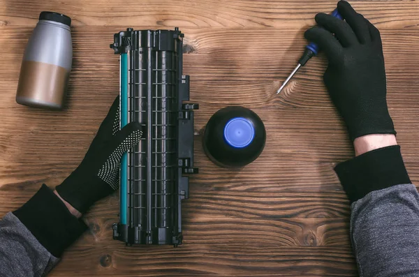 Computer technician engineer is refilling a laser toner cartridge. Office equipment maintenance concept.