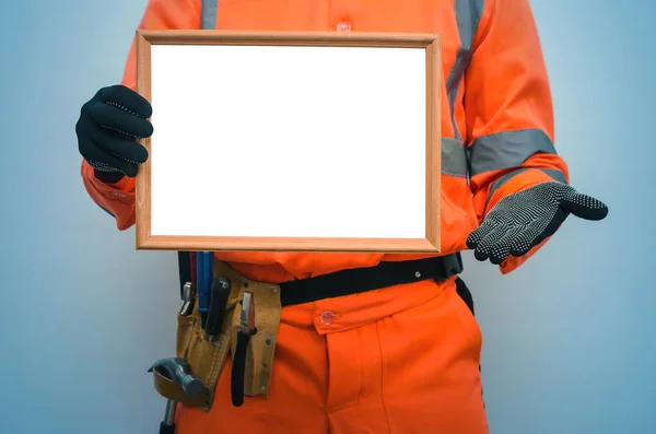 Blank builder certificate. Construction diploma. Contractor is showing a blank photo frame border in his hands. Housing project presentation.