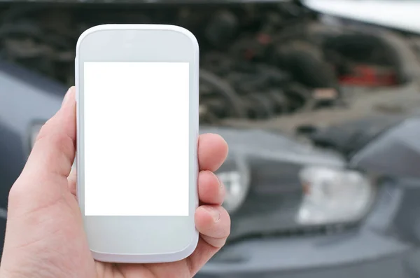 Evacuation call concept.Mobile phone with blank screen on on broken car background. Call to a car mechanic.