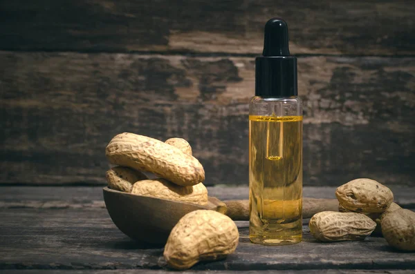 Peanut oil in the bottle on the wooden table background.