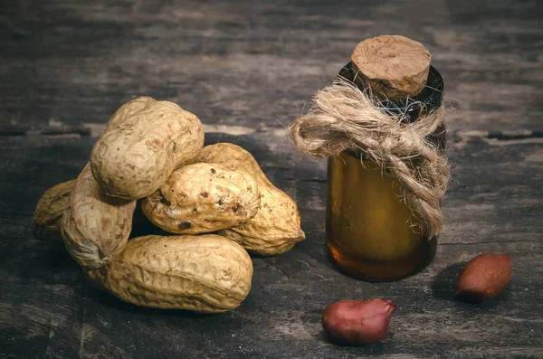 Peanut oil in the bottle on the wooden table background.