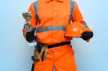 En iyi builder yüklenici Ödülü kavramı. Altın kupa kupa ve kask üzerinde mavi arka plan izole işçisi elinde.