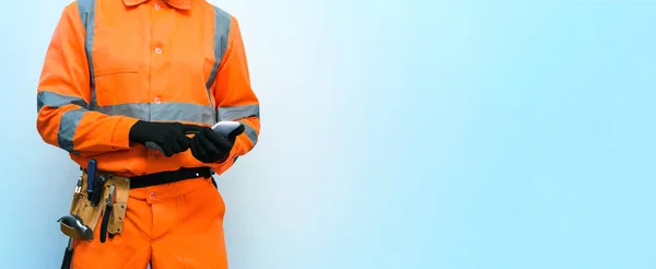 Trabalhador Construtor Está Segurando Mão Telefone Celular Isolado Fundo Azul — Fotografia de Stock