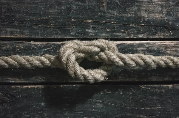 Rope knot on the wooden surface background.