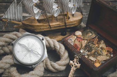 Korsan gemisi, define haritası, hazine sandığı altın dolu ve ahşap masa arka plan üzerinde bir pusula.