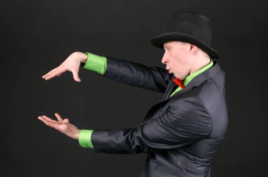 Başının üstünde bir Melon şapkan sihirbazla siyah arka plan üzerine bir büyü döküm.