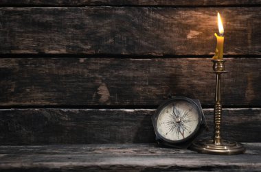 Ahşap masa arka plan kopya alanı ile pusula ve yanan mum. Seyahat veya macera kavramı.