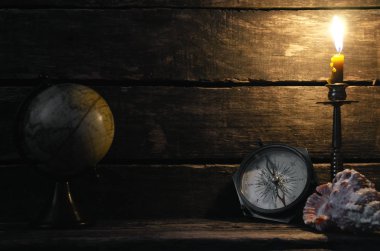 Pusula, küre ve ahşap masa arka plan kopya alanı ile yanan mum. Seyahat veya macera kavramı.