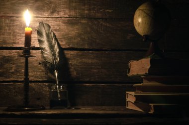 Quill'in kalem inkpot, küre ve yazar Resepsiyon arka plan üzerinde yanan mum ışığında kitap yığını. Eğitim kavramı.