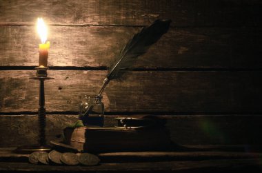 Quill'in kalem inkpot ve kitap yazar Resepsiyon arka plan üzerinde yanan mum ışığında. Eğitim kavramı.