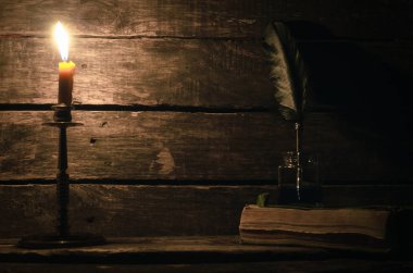 Quill'in kalem inkpot ve kitap yazar Resepsiyon arka plan üzerinde yanan mum ışığında. Eğitim kavramı.