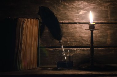 Quill'in kalem inkpot ve kitap yazar Resepsiyon arka plan üzerinde yanan mum ışığında. Eğitim kavramı.