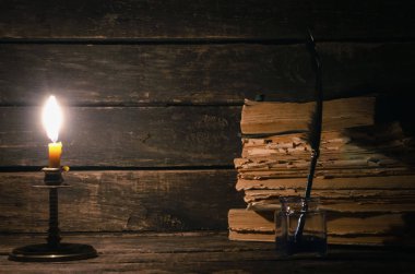 Quill'in kalem inkpot ve yazar Resepsiyon arka plan üzerinde yanan mum ışığında kitap yığını. Eğitim kavramı.