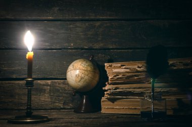 Quill'in kalem inkpot, küre ve yazar Resepsiyon arka plan üzerinde yanan mum ışığında kitap yığını. Eğitim genel kavram ya da seyahat günlüğü.