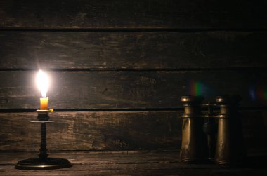 Dürbün ve ahşap masa arka plan kopya alanı ile yanan mum. Seyahat veya macera kavramı.