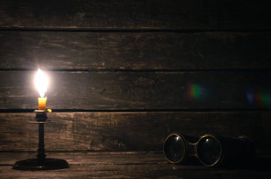Dürbün ve ahşap masa arka plan kopya alanı ile yanan mum. Seyahat veya macera kavramı.