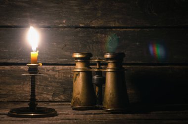 Dürbün ve ahşap masa arka plan kopya alanı ile yanan mum. Seyahat veya macera kavramı.