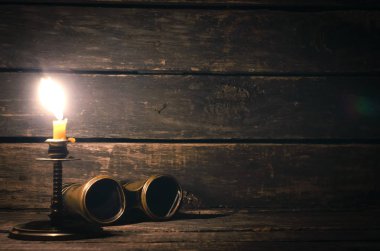 Dürbün ve ahşap masa arka plan kopya alanı ile yanan mum. Seyahat veya macera kavramı.