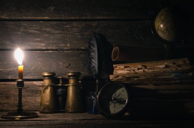 Seyahat ya da macera kavramı geçmiş. Pusula, dürbün, harita, kitap yığını, tüy kalem maceraperest masada.