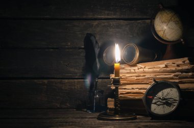 Seyahat ya da macera kavramı geçmiş. Pusula, dürbün, harita, kitap yığını, tüy kalem maceraperest masada.